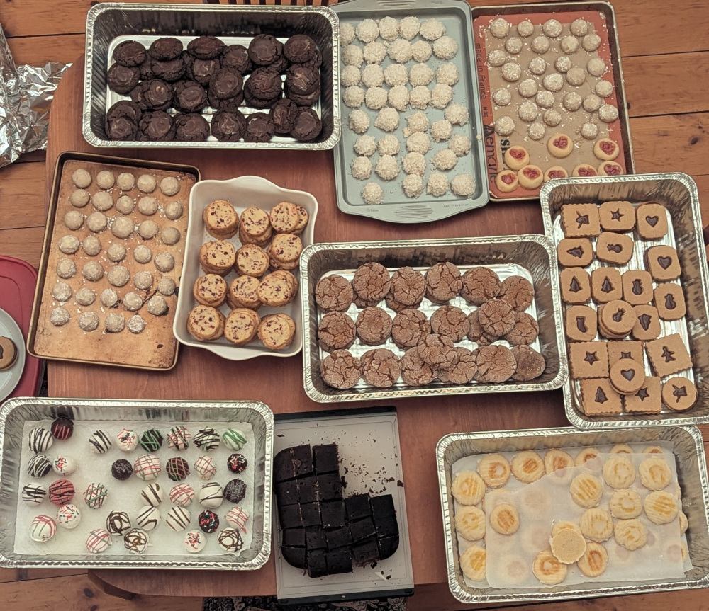 10 trays of cookies. Clockwise from top left: Andes peppermint cookies, coconut snowballs, Russian tea cakes, heart thumbprints, hazelnut caramel linzers, lemon thumbprints, Vietnamese coffee brownies, birthday cake truffles, more Russian tea cakes, cranberry orange icebox cookies, ginger molasses cookies
